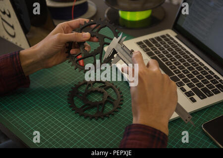 Mechanic checking diameter of chain ring with vernier calipers in workshop Stock Photo