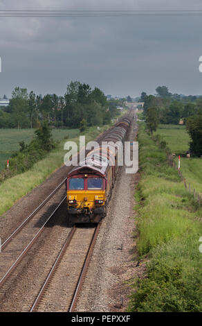 A DB Cargo UK class 66 locomotive passing Ashchurch for Tewkesbury with a freight train of empty steel coil wagons heading for reloading Stock Photo