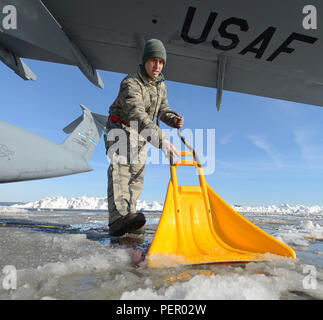 During Winter Storm Jonas on January 25, 2016, a C-5M Super Galaxy of the 436th Airlift Wing at Dover AFB is prepared for flight after snow removal. Senior Airman from the 436th Aircraft Maintenance Squadron clears ice under the aircraft's wing. Heavy equipment and hand tools removed 22 inches of snow from the flight line and runways to resume operational activity efficiently. The aircraft is powered by four General Electric CF6-80C2 turbofan engines. Stock Photo