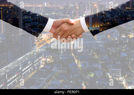 Double exposure of businessman handshake agreement with cityscape in background. Stock Photo