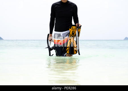 Man holding snorkeling gear come out from the sea in tropical is Stock Photo