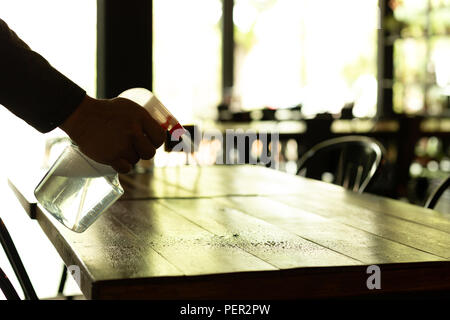Waiter cleaning the table with spray disinfectant on table in