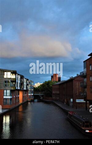 Birmingham England canal view in the early hours of the morning with a beautiful blue sky, white clouds and residential buildings along the canal Stock Photo