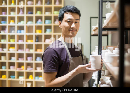 Young potter showing pottery in studio Stock Photo