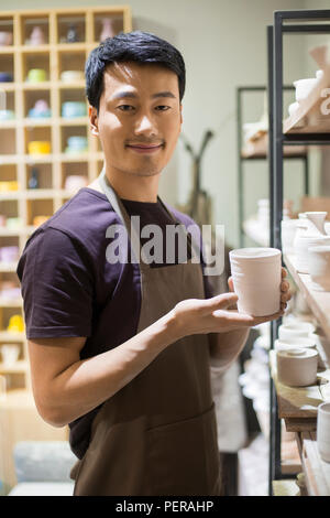 Young potter showing pottery in studio Stock Photo