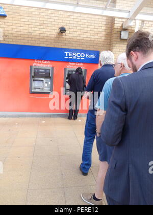 People waiting in a queue to use the one remaining working ATM at the Tesco supermarket in Rotherham, South Yorkshire, England Stock Photo