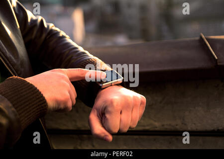 Smartwatch  touchscreen on men's hand and the other hand is working on it. A man using his smartwatch app. Close up hands. Stock Photo