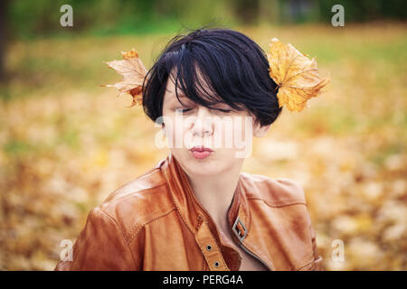 Closeup portrait of middle aged caucasian dark haired brunette woman with short bob hairstyle in light brown leather jacket,  her eyes closed, outside