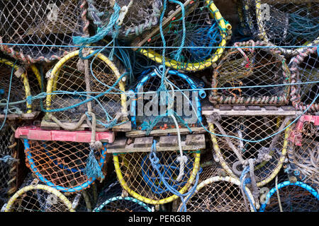 Stacked lobster fishing pots netted boxes at harbour wall Stock Photo