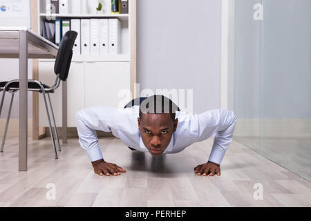 Young African American Man Doing Pushup In Front Of Closed Glass Door Stock Photo