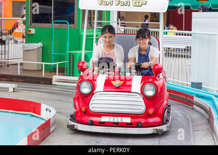 TOKYO, JAPAN - 19 July 2016 - Two happy Japanese girls riding on a Furi Furi GP car at Tokyo Dome City Amusement Park in Tokyo, Japan on July 19, 2016 Stock Photo