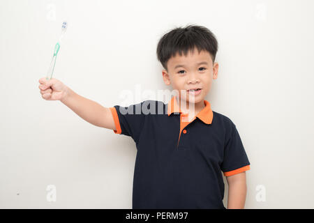 Cheerful little boy holding a tooth brush over white background, Studio portrait of a healthy mixed race boy with a toothbrush isolated. Stock Photo