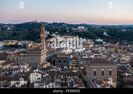 Florence, Italy - March 23, 2018: Evening light illuminates the cityscape of Florence, including the landmark tower of Palazzo Vecchio, with the Arcet
