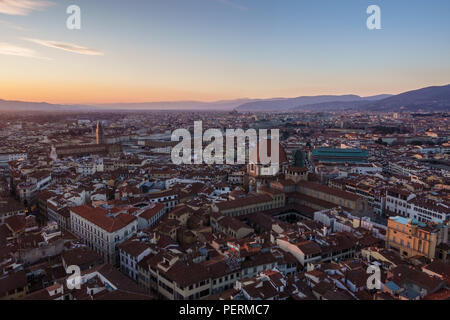 Florence, Italy - March 23, 2018: The sun sets over the hills of Tuscany and the cityscape of Florence, viewed from above, with Capelle Medicee in the Stock Photo