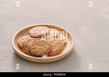 Oat cookies in plate isolated on white background, top view. Sweet bakery products. Round cookies in a wooden plate. Stock Photo