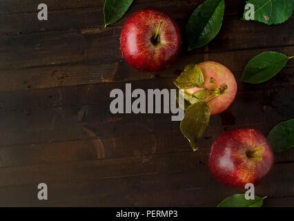 Two red apples with one yellow pink apple and leaves on wooden background.Copyspace left. Stock Photo