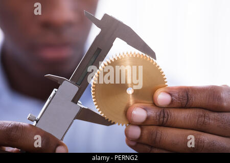 Close-up Of A Person Holding Golden Gear Measuring With Vernier Caliper Stock Photo