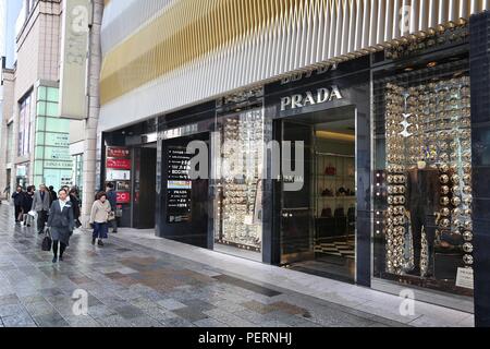 TOKYO, JAPAN - DECEMBER 1, 2016: People walk by Prada luxury fashion store at Ginza district of Tokyo, Japan. Ginza is a legendary shopping area in Ch Stock Photo