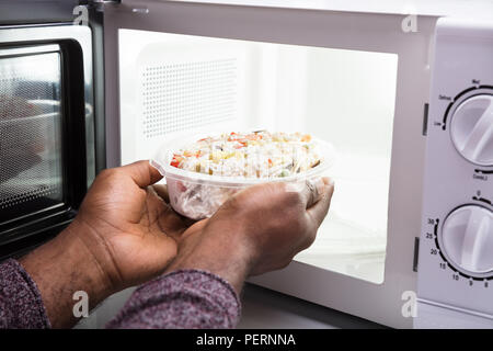 Cooking, heating food in the microwave. Baked potatoes with meat,  vegetables on a white plate in the microwave top view Stock Photo - Alamy