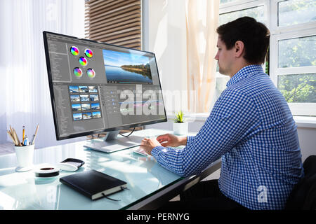 Young male editor editing video on computer at workplace Stock Photo