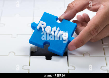 Close-up of a person placing last blue retire piece into jigsaw puzzle Stock Photo