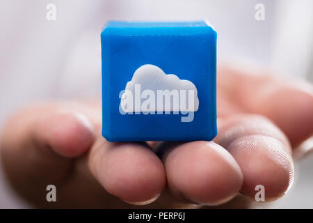 Close-up of a businessperson's hand holding blue cloud icon cubic block Stock Photo