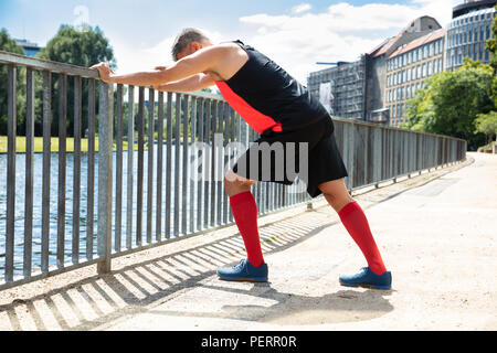 Side View Of A Man Doing Push-Ups On Railing At Outdoors Stock Photo