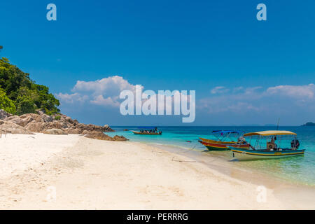 Tourists arriving by motorboat on Rawa Island,  near Perhentian Kecil in Malaysia. Crystal clear water, azure blue sea and fine sand make this beach... Stock Photo