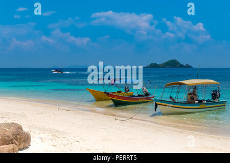 Tourist boats are anchored on the lovely white fine sandy beach of the uninhabited Rawa Island next to Perhentian Kecil in Malaysia. On the azure blue... Stock Photo