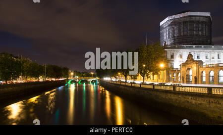 Traffic illuminates the Quays beside Ireland's Four Courts building on the banks of Dublin's River Liffey at night. Stock Photo