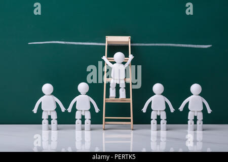 Human Figure Climbing Ladder To Reach Finish Line On Chalkboard Stock Photo
