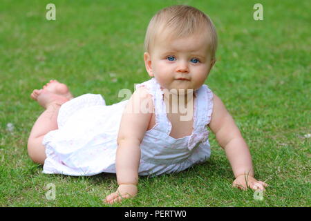 9 month old blue eyed baby girl holding herself up in the crawling position Stock Photo