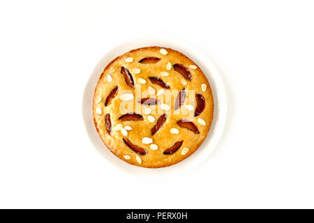 Whole homemade plum cake, glazed with victoria plum jam and decorated with roasted almond slivers, isolated on white background. Stock Photo