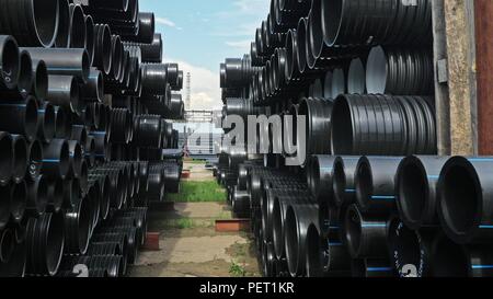 Warehouse of finished plastic pipes industrial outdoors storage site. Manufacture of plastic water pipes factory. Stock Photo