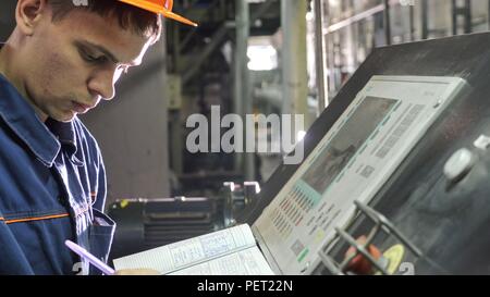 RUSSIA, ANGARSK - JUNE 8, 2018: Operator monitors control panel of production line. Manufacture of plastic water pipes factory. Stock Photo