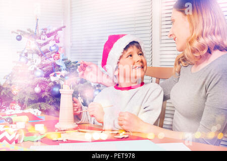 Happy family, young mother and preschool boy, decorating wooden Christmas toys together Stock Photo