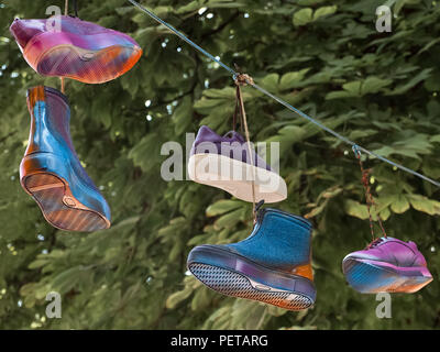 Cultural diversity symbolically shown. Footwear hanging on the cord. Stock Photo