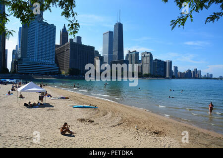 Skyscrapers in the Streeterville neighborhood loom in the background of bathers in Lake Michigan at Chicago's Ohio Street Beach. Stock Photo