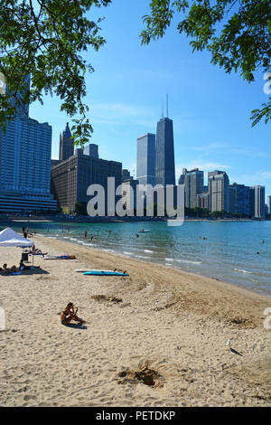 Skyscrapers in the Streeterville neighborhood loom in the background of bathers in Lake Michigan at Chicago's Ohio Street Beach. Stock Photo