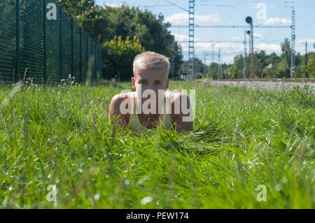 Young man in yellow t-shirt sitting on the green grass Stock Photo