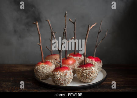 Homemade Caramel Apples on a Stick for Autumn holidays on rustic wooden background. Organic Snack - Caramel Apples with Almonds. Stock Photo