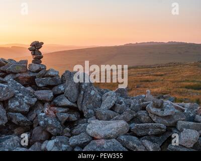 A pile of stones on an old dry stone wall with setting sun in the background, on Bodmin Moor, Conrnwall Stock Photo