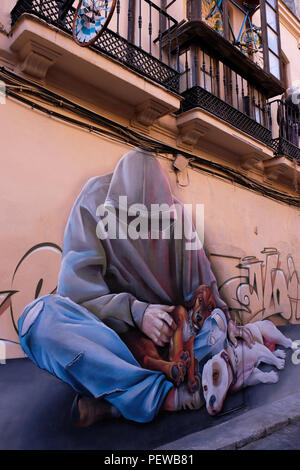 View of colorful street art, a man with a hoody and a dog, shot in the streets of Malaga in Andalusia, Spain, near the plaza de la Merced Stock Photo