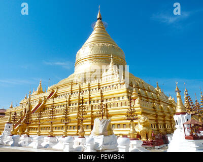 Lansdape view of the shwedagon pagoda in Yangon, Myanmar, with golden stupas in the foreground and blue sky in the background Stock Photo