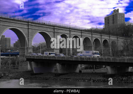 Landscape view of the High Bridge, the oldest bridge in New York, with blue cloudy sky in the background and several NYPD vehicles in the front Stock Photo