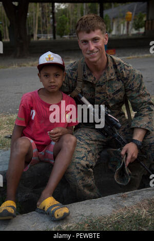 U.S. Marine Corps Cpl. Preston Bentley, a section leader with Golf Company, 2nd Battalion, 4th Marine Regiment, poses for a photo with an Indonesian child during Landing Force Cooperation Afloat Readiness and Training (LF CARAT) 2015 on Ksatraian Base, East Java, Indonesia, Aug. 4, 2015. LF CARAT is meant to strengthen, increase the interoperability in amphibious planning and operations and the core skill sets between the United States and the nations of Indonesia, Malaysia, and Thailand. (U.S. Marine Corps photo by MCIPAC Combat Camera Lance Cpl. Sergio RamirezRomero/Released) Stock Photo