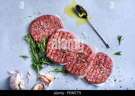 Raw burger cutlets, ground beef meat with rosemary and spices, hamburger ingredients. Top view, flat lay Stock Photo