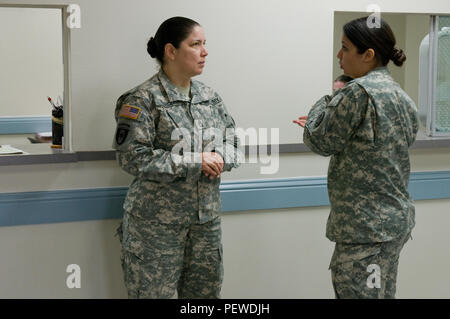 Clinic Noncommissioned Officer in Charge Sgt. 1st Class Evangelina Garcia and medic Sgt. Jennifer Hess discuss periodic health assessment matters at the Texas Medical Command clinic at Camp Mabry, Austin, Texas, Feb. 6, 2016. This assessment measures a number of aspects of a Soldier’s health including laboratory work, hearing, vision and dental. (U.S. Army National Guard photo by Staff Sgt. Josiah Pugh/Released) Stock Photo