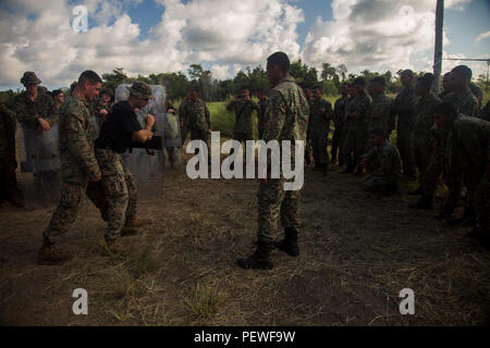 U.S. Marine Corps Sgt. Garrett Spino, left, and Cpl. Billy Elliot, far left, both squad leaders with Golf Company, 2nd Battalion, 4th Marine Regiment, show Malaysian soldiers how to properly stand as a riot control unit during Landing Force Cooperation Afloat Readiness and Training (LF CARAT) 2015 at Tanduo Beach, East Sabah, Malaysia, Aug. 16, 2015. LF CARAT is meant to strengthen, increase the interoperability in amphibious planning and operations and the core skill sets between the United States and the nations of Indonesia, Malaysia, and Thailand. (U.S. Marine Corps photo by MCIPAC Combat  Stock Photo