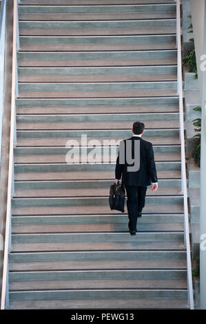 View from above lookng down on a businessman walking up stairs in a conference centre lobby. Stock Photo